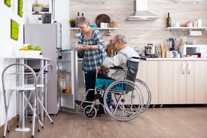 Senior woman preparing breakfast for handicapped husband taking eggs from refrigerator